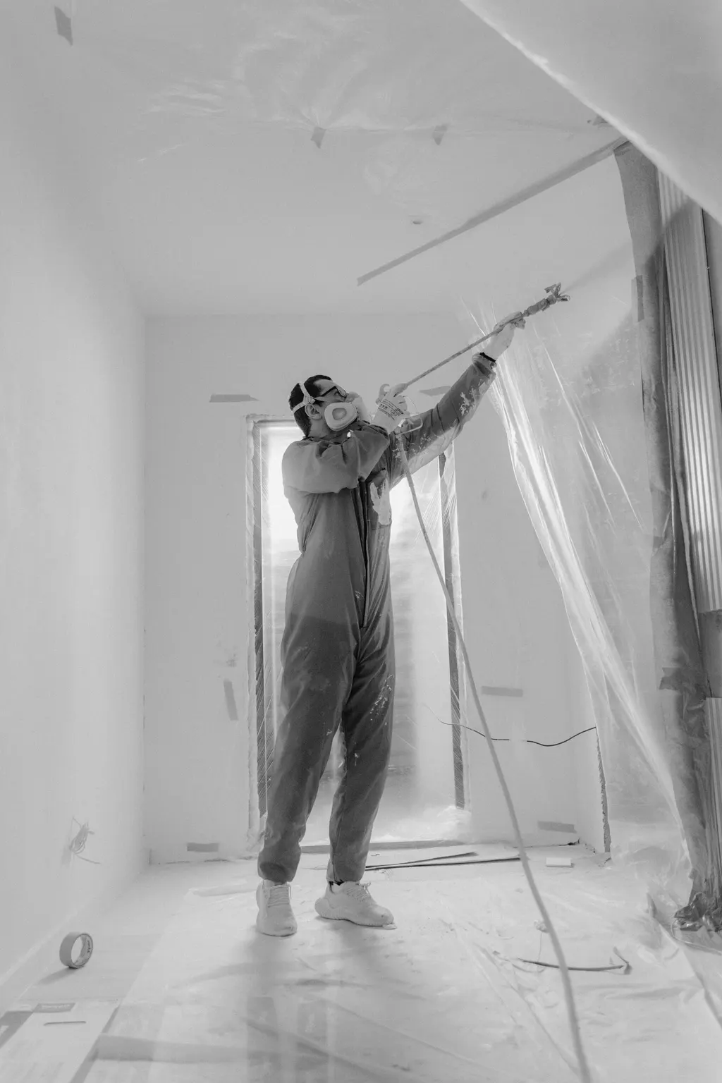 Maschineller Auftrag an Wand und Decke in einem abgeklebten Flur